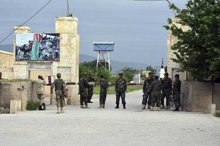 Afghan soldiers stand guard at the gate of a military compound after an attack by gunmen in Mazar-e- Sharif province