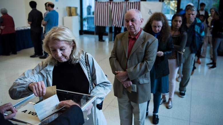 A French citizen casts her ballot while others wait in line while voting in the country's presidential election