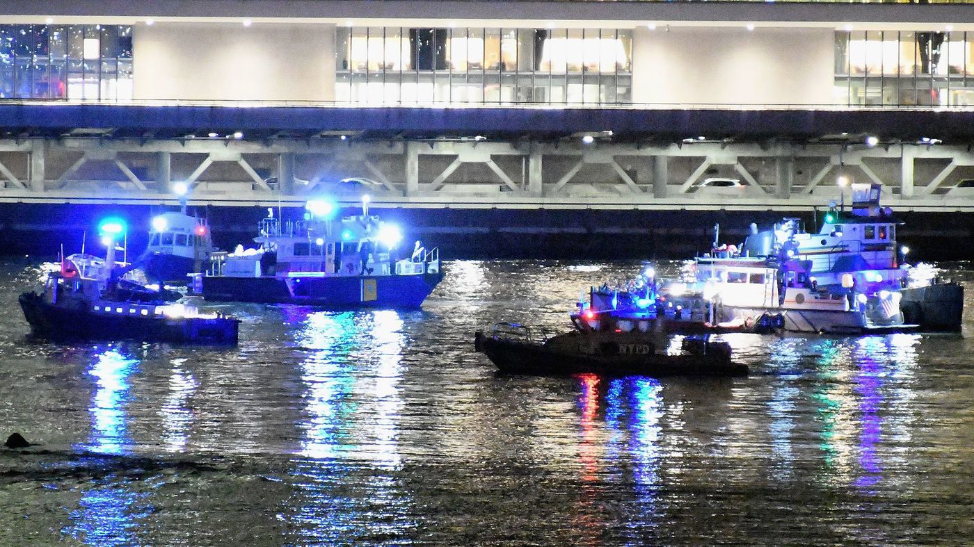 Emergency personnel work at the scene of a helicopter crash in the East River in New York