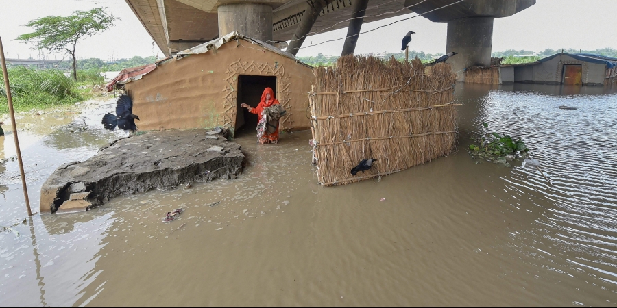 A woman stands outside her submerged shanty at Yamuna Khadar as the water level of Yamuna river rises in New Delhi 