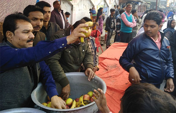 श्रद्धालुओं में फल बांटते चेयरमैन