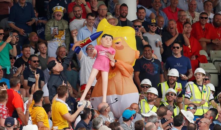 A man dressed as the Trump baby blimp holding a Kim Jong-un dummy