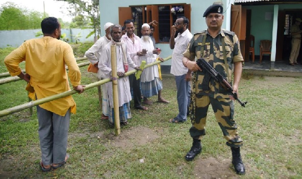 People stand in a queue to check their names on the draft list of NRC