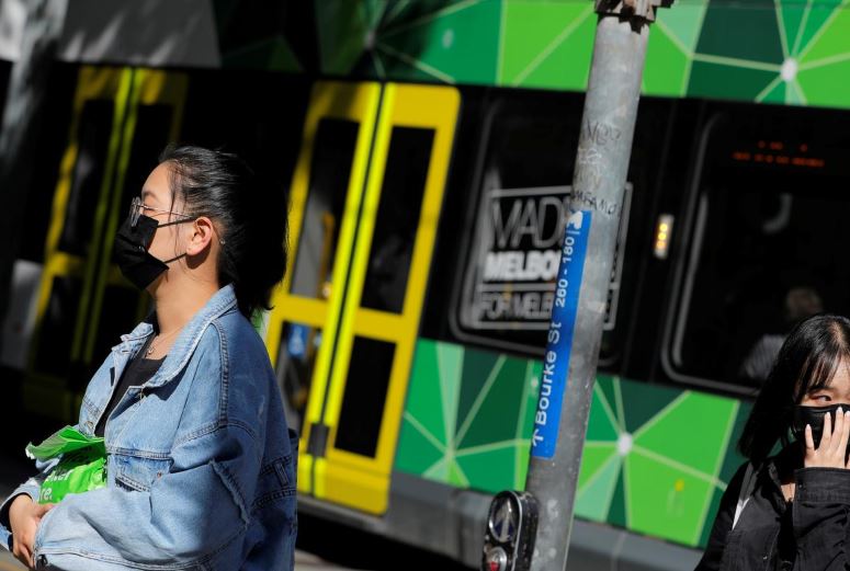 People wearing face masks walk on Bourke Street after cases of the coronavirus were confirmed in Melbourne, Victoria, Australia