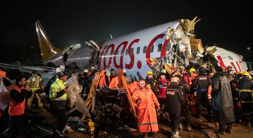 First responders gather around the Pegasus Airlines Boeing 737-86J plane wreckage after it overran the runway during landing and crashed, at Istanbul's Sabiha Gokcen airport