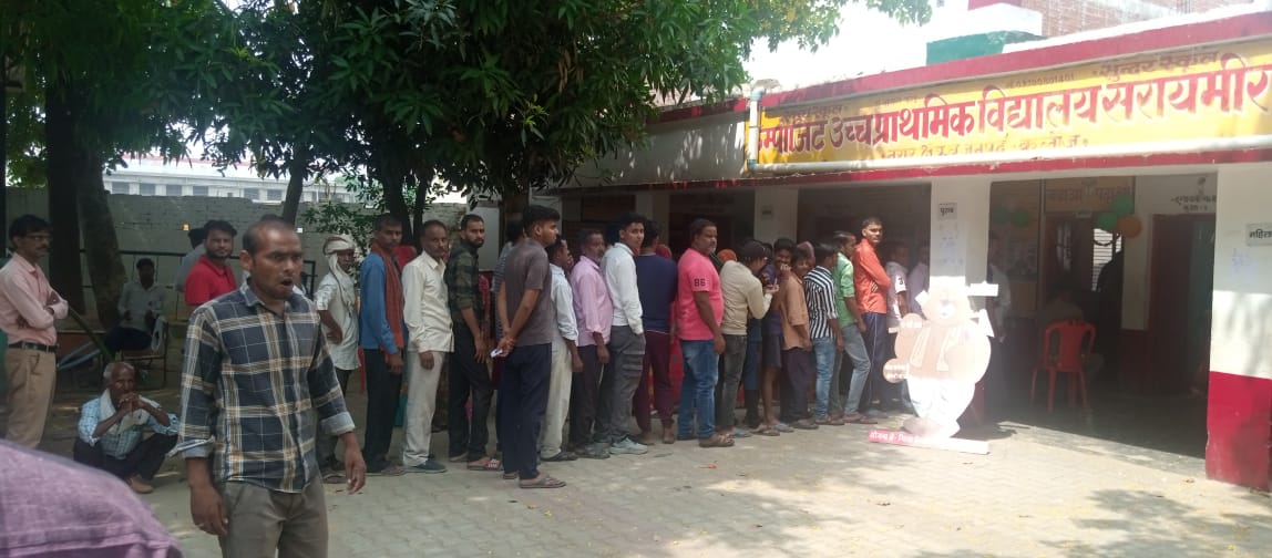 People wait for their turn to vote at a polling booth in Kannauj